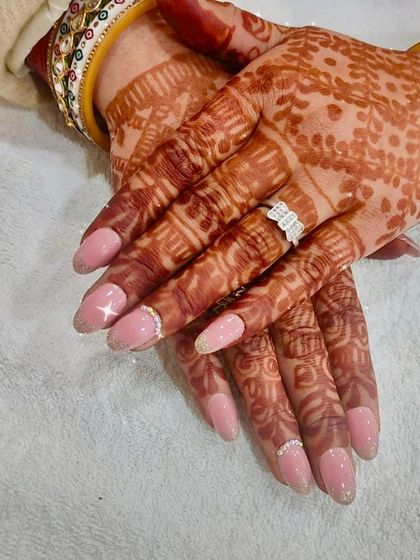 The perfect bridal nails to complement henna, this design features a soft pink base, a sparkling accent nail, and delicate rhinestone bands.