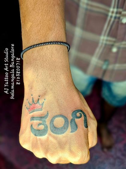 A bold statement of love for a younger sister, with the word 'ತಂಗಿ' (Tangi) tattooed across the knuckles, complete with a crown.