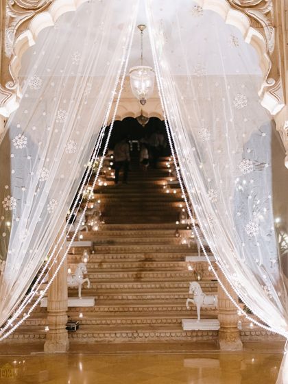 A fairytale entrance for the white reception. Sheer, embellished curtains and a candlelit staircase created a soft and dreamy welcome for guests, setting a tone of pure romance from the very first step.