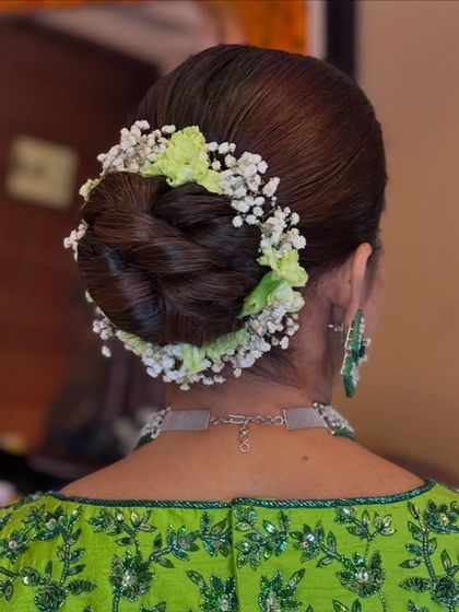 A close-up of the fresh green and white floral arrangement on a classic hair bun.