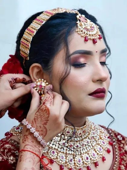The final touches are what bring the entire bridal look together. Here, I'm placing the jewelry on my bride, whose makeup features a stunning cranberry smokey eye and a deep red lip.