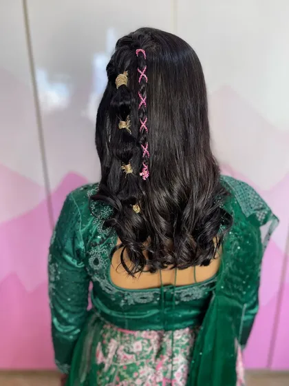A fun and funky hairstyle for a Mehendi or Haldi. This look features a cool lace-up braid using colorful thread and gold cuffs, adding a pop of personality to the style.