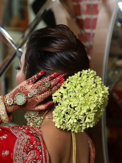 A classic bridal bun adorned with a gajra of fresh green flowers. This is a timeless and elegant choice that adds a touch of natural beauty to any bridal look.