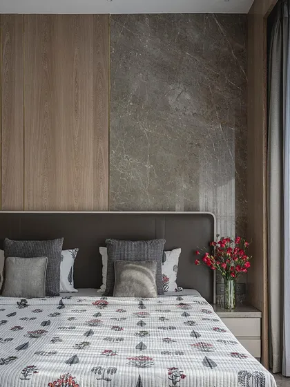 This bedroom combines warm wood paneling with a cool grey marble accent wall behind the bed, creating a balanced and serene environment.