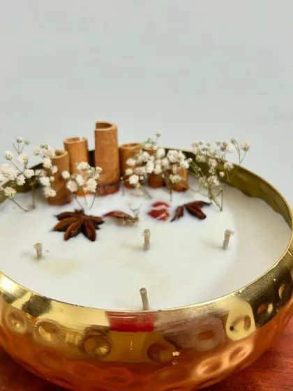 This is one of my most premium offerings, a 6-inch golden metal urli candle. It’s filled with 100% soy wax and decorated with real cinnamon sticks and spices, making it a perfect centerpiece or a luxurious corporate gift for Diwali.