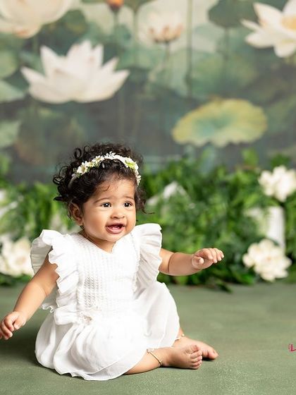 A moment of quiet contemplation from this sweet baby girl. The simple white dress and the beautiful lotus pond backdrop create a serene and artistic portrait.