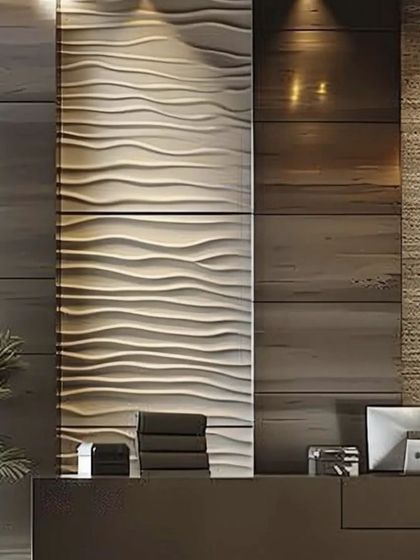 Lighting plays a crucial role in office design. Here, a textured, wave like wall panel is highlighted with spotlights to create a dramatic and sophisticated feature at the reception desk.