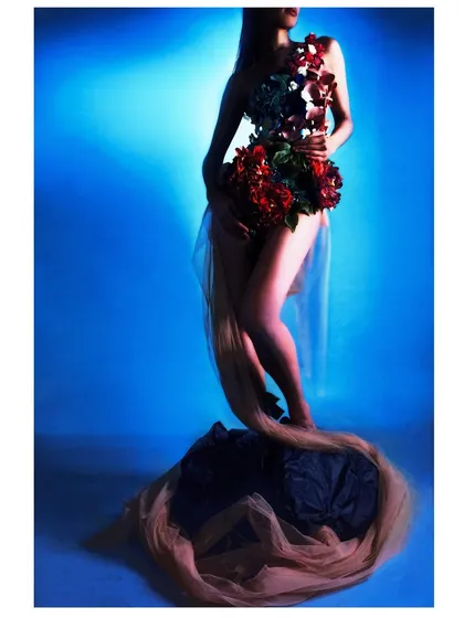A powerful silhouette against a deep blue background. This shot focuses on the form of the body and the floral arrangement, creating a dramatic and artistic composition.