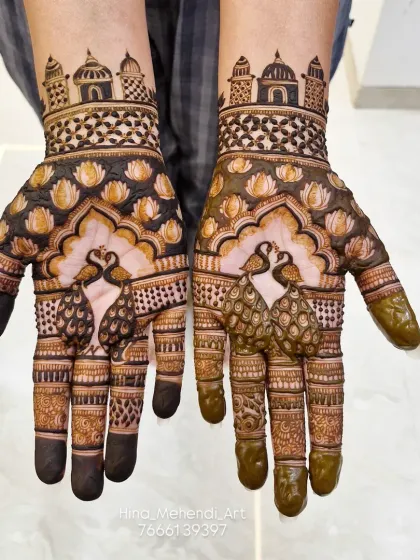 A simple yet stunning design with two peacocks meeting on the palms, surrounded by lotus flowers and topped with temple domes.
