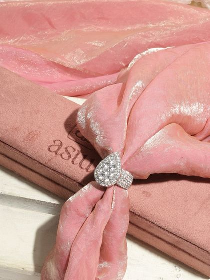 The Raiya Cocktail Ring elegantly displayed on a pink velvet cloth, highlighting its impressive 7-carat diamond cluster setting.
