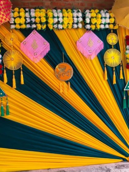 A unique backdrop created with diagonal draping in yellow and green fabric. The look is completed with colorful hangings and Rajasthani umbrellas for a vibrant, geometric effect.