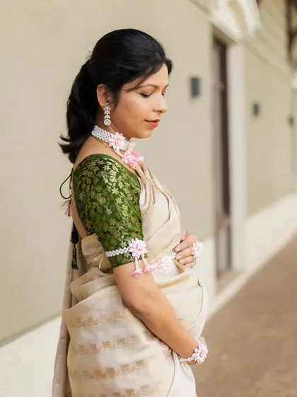 A side profile of the expecting mother, elegantly dressed in a traditional saree and floral jewellery for her baby shower.