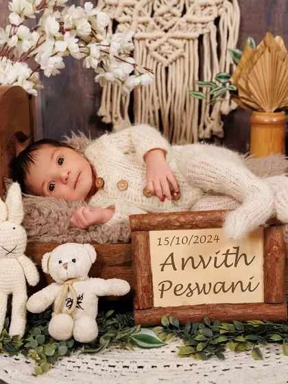 A full view of a newborn session setup, featuring baby Anvith in a rustic bed with personalized details, surrounded by soft textures and props.