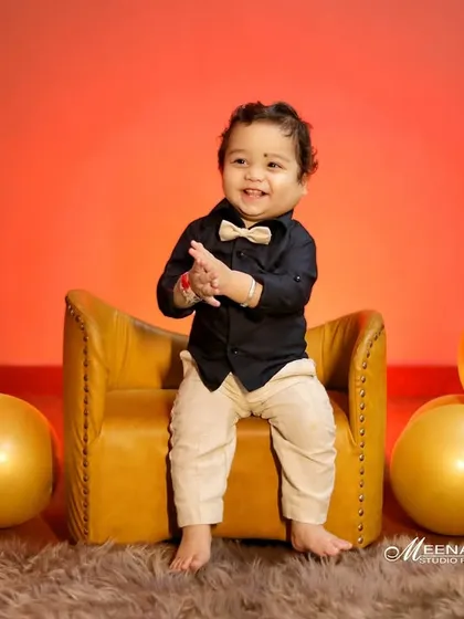 The best moments are often the candid ones. Here, the birthday boy is sharing a joyful, spontaneous clap while sitting in a miniature armchair, surrounded by festive golden balloons. This shot perfectly captures the happy spirit of a one year old.