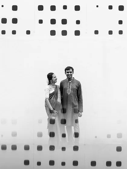 An artistic black and white portrait of a couple standing against a modern, patterned wall. We use composition and negative space to create striking, minimalist images.