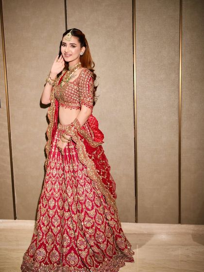 A smiling bride feeling confident and radiant in her custom-styled red lehenga. This is the ultimate goal of our journey together.