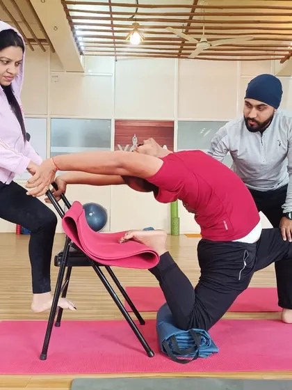For many, deep backbends seem impossible due to stiffness or fear of injury. Here, I am assisting a student using a yoga chair for support, allowing them to safely open their spine and build confidence. My one-on-one therapeutic approach ensures that every pose is adapted to your body's specific needs.