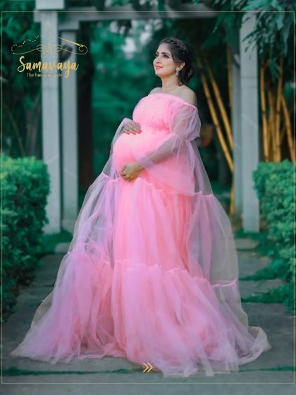 This soft pink frill gown looks like it's straight out of a fairytale. The garden path and archway create a magical setting for this maternity photo.