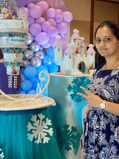 Here I am with the completed Frozen-themed chandelier cake at the venue. Seeing the final setup come together with the party's decor is one of the most rewarding parts of my job as a custom cake designer.