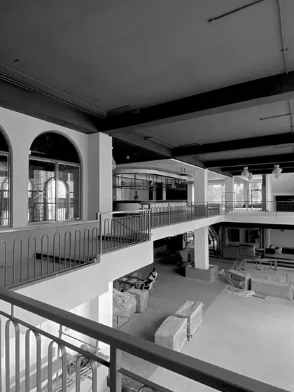 A work-in-progress shot of a brewery project, captured in black and white to emphasize the architectural form. The image shows the double-height space, arched windows, and mezzanine level taking shape.