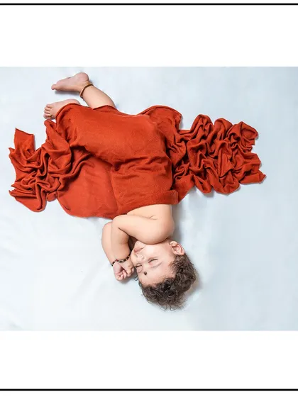 An artistic pose from a newborn photoshoot, showcasing how I can creatively style the swaddle wrap for a unique and beautiful image while keeping the baby secure.