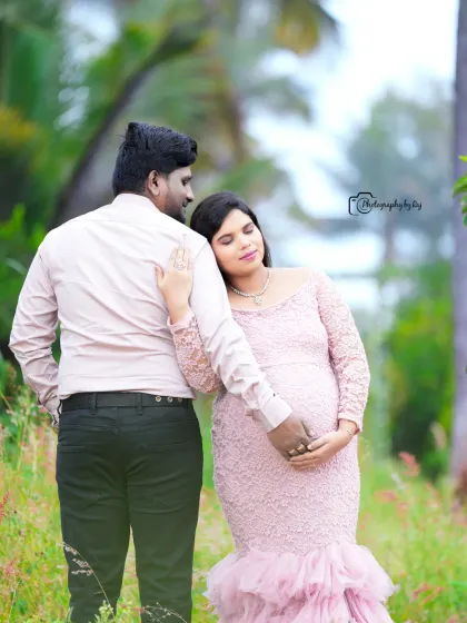 A tender moment between an expecting couple in a beautiful garden. The mother-to-be is wearing a delicate pink lace gown.