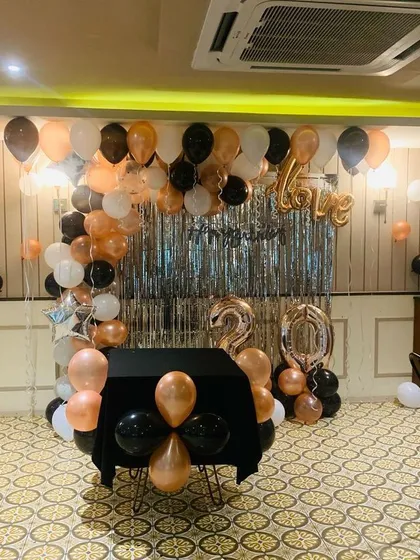 This photo shows the birthday party decoration before the cake was placed on the table. The setup includes a balloon arch, fringe curtain, and foil balloons, all ready for the celebration to begin.