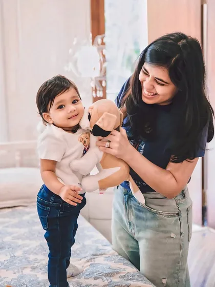 A mother and her toddler playing with a stuffed animal in a cozy indoor setting. At-home sessions are perfect for capturing your child in their most comfortable environment.