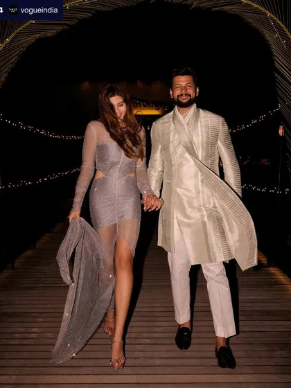 A candid shot of the couple from their Vogue-featured wedding. Her sparkling after-party dress is paired with a relaxed yet glamorous hair and makeup look.