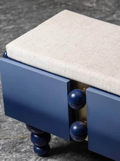 A detail shot of the ombre bench, showing the transition from deep navy to a lighter blue. The spherical wooden knobs between the storage compartments add another layer of tactile and visual interest.