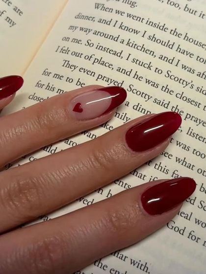 A classic Valentine's look. Deep red nails with a single accent nail featuring a sheer base and a tiny heart.