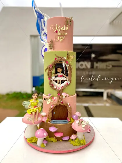 For a little princess's first birthday, I created this three-tiered enchanted fairy house cake. Every element, including the little girl on the swing and the fairy perched on a mushroom, is completely handmade from fondant to bring this magical world to life.