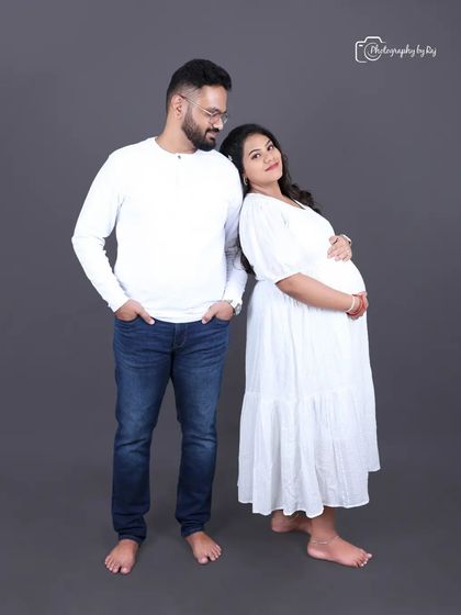 A classic couple's portrait in simple white outfits against a grey studio background, focusing on their connection.
