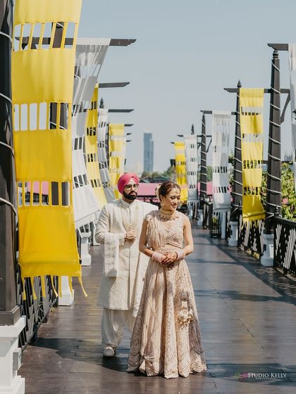 A full-length portrait of the couple on a bridge in Bangkok, their elegant outfits complementing the modern, clean lines of the location.