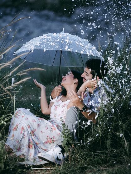 A happy, laughing moment under an umbrella, as a couple enjoys a playful, snowy pre-wedding shoot.