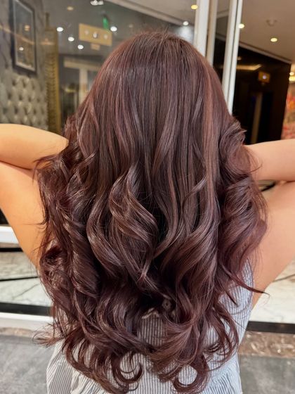 A beautiful brown global hair color styled with voluminous curls. This look is classic, elegant, and full of life.