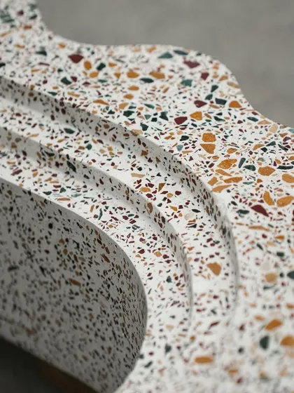 Close-up details of the custom terrazzo bookshelf, highlighting the smooth curves and the beautiful texture of the multi-colored stone chips.