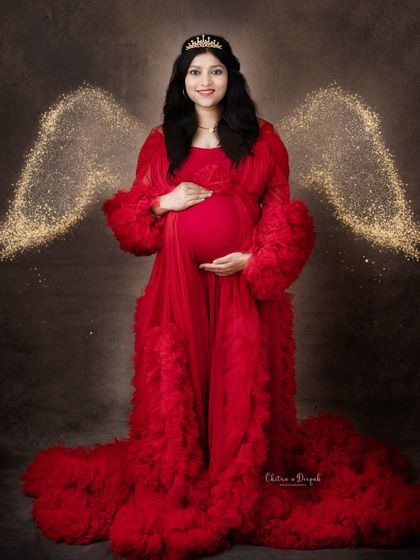 A fiery red angel. We love this combination of a bold red gown, a golden halo, and sparkling wings for a truly divine maternity portrait.
