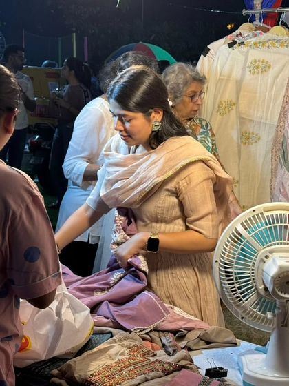 A customer examines the intricate work on a piece of clothing, highlighting the focus on quality and craftsmanship.
