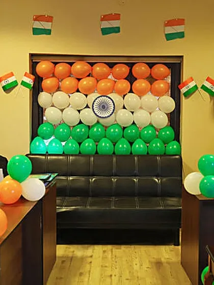 An office cabin gets a patriotic makeover with a balloon backdrop in the shape of the Indian flag. Small flag buntings and balloon clusters complete the festive look for a Republic Day office party.