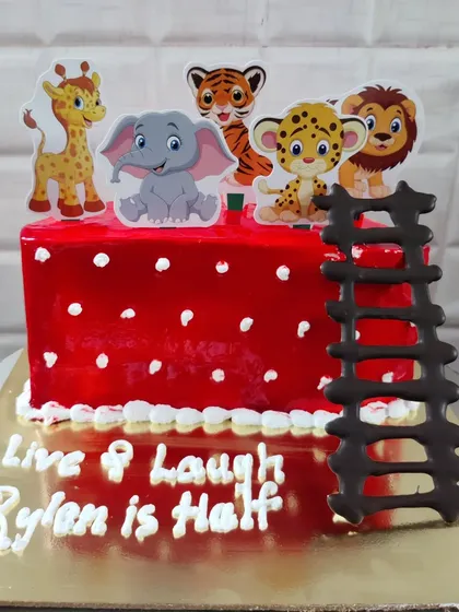 A half-birthday cake with a cute jungle animal theme. This square cake features a bright red glaze and adorable animal toppers.