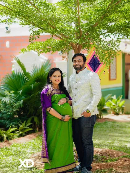 A lovely couple's portrait under a tree in a colorful, village-themed setting.