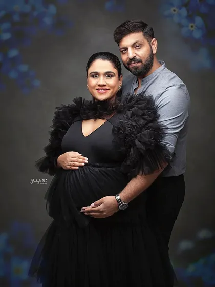 A classic maternity pose that radiates confidence and joy. The dramatic tulle of the black gown adds a touch of high fashion to this studio portrait.