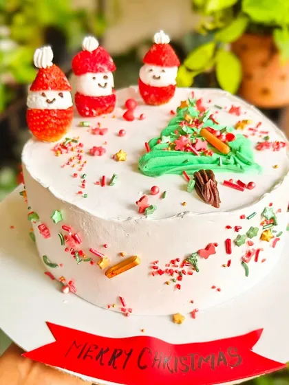 A fun and whimsical Christmas cake design. I used fresh strawberries to create cute little Santas, alongside a piped buttercream Christmas tree and colorful sprinkles.