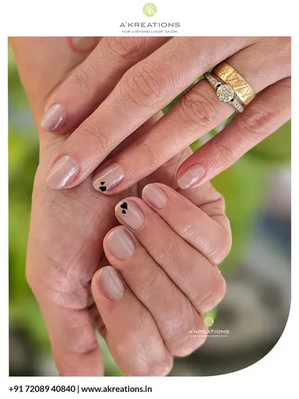 Proving that simple can be stunning. This manicure features clean, natural-shaped nails with a sheer nude gel polish and two tiny, hand-painted black hearts for a touch of minimalist charm.