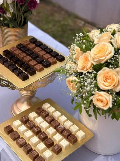 A sweet treat table at a Mehendi event, with custom chocolates and beautiful floral arrangements.