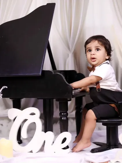 A little boy looking sharp and ready to play the piano for his first birthday photos.
