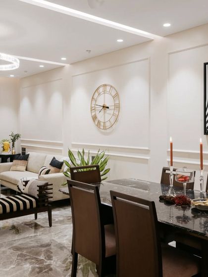 The lighting in this living and dining area is layered to create the right mood. A large statement clock on the wall adds a classic touch, while the mix of overhead and spot lighting keeps the space bright and functional.