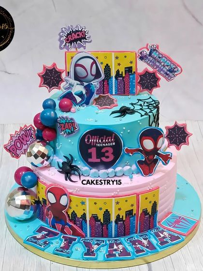 A dynamic two-tier Spider-Man themed cake for a 13th birthday. This chocolate cake features characters from the Spider-Verse, a city skyline, and comic book sound effects.