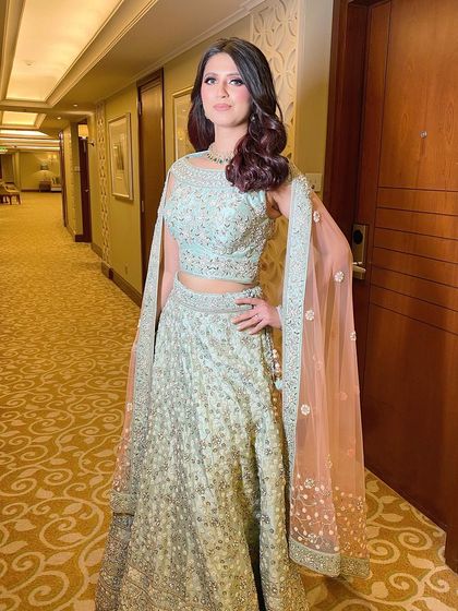 A full-length photo of Ishita's elegant reception look. The soft makeup allows her beautiful outfit and smile to be the focus.